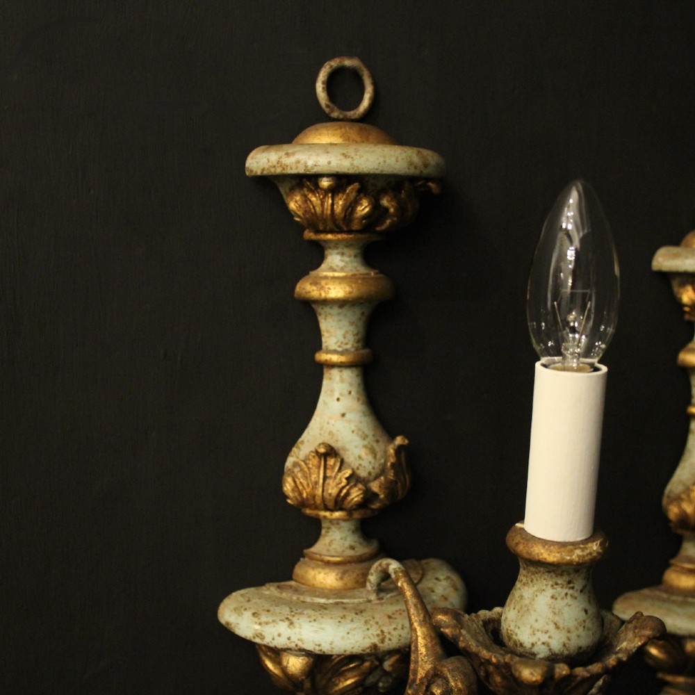 A pair of antique Italian wall lights featuring turned polychrome stems in pale green and gold with carved leaf accents and single candlestick arms. View IV