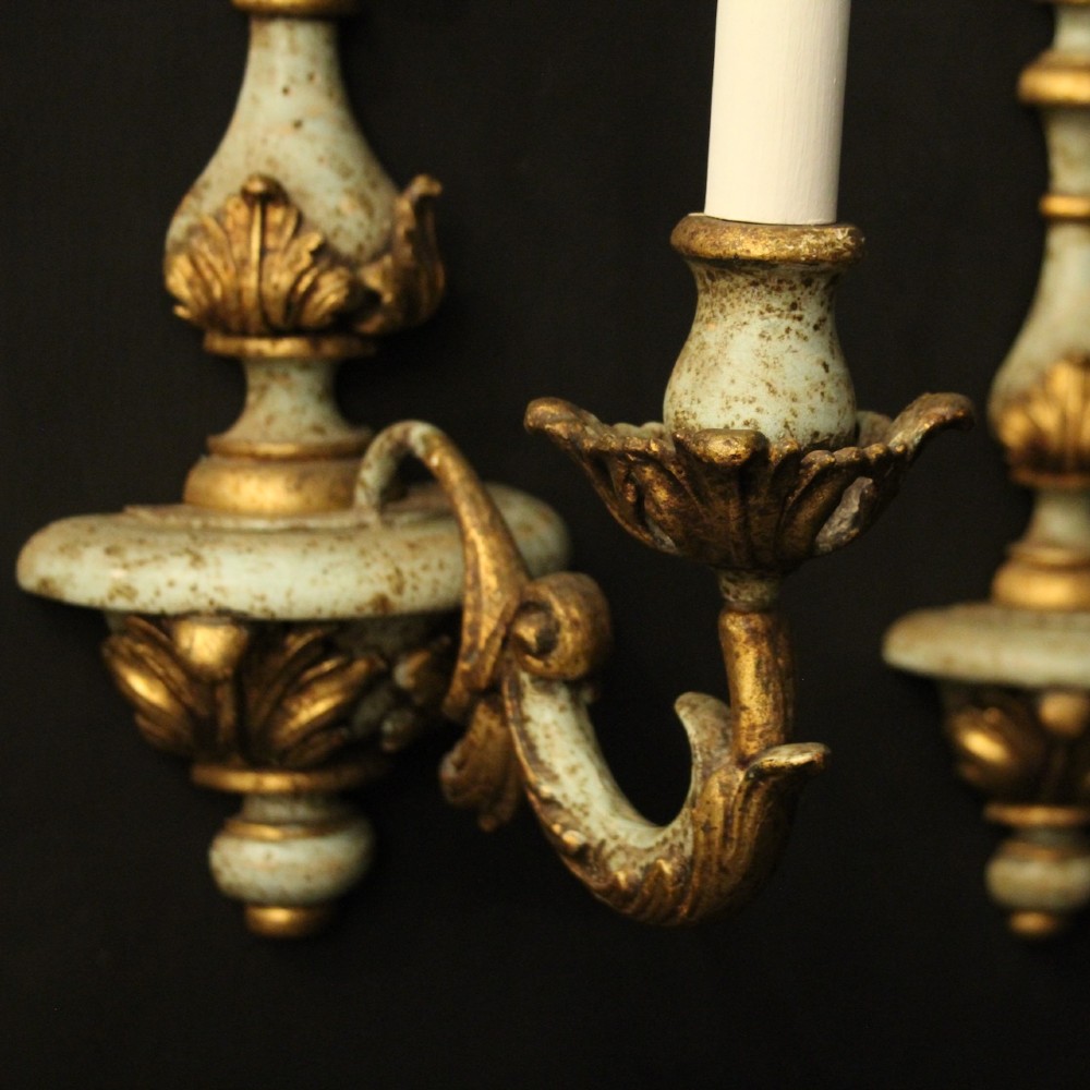 A pair of antique Italian wall lights featuring turned polychrome stems in pale green and gold with carved leaf accents and single candlestick arms. View VII
