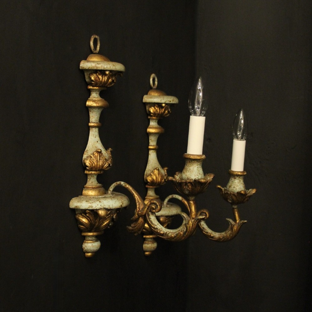 A pair of antique Italian wall lights featuring turned polychrome stems in pale green and gold with carved leaf accents and single candlestick arms. View IX