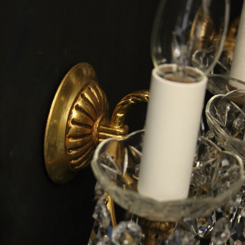 A set of four French triple-arm wall lights with gilt brass frames, candle sleeves, glass drip pans, and clear faceted crystal drops. View IX