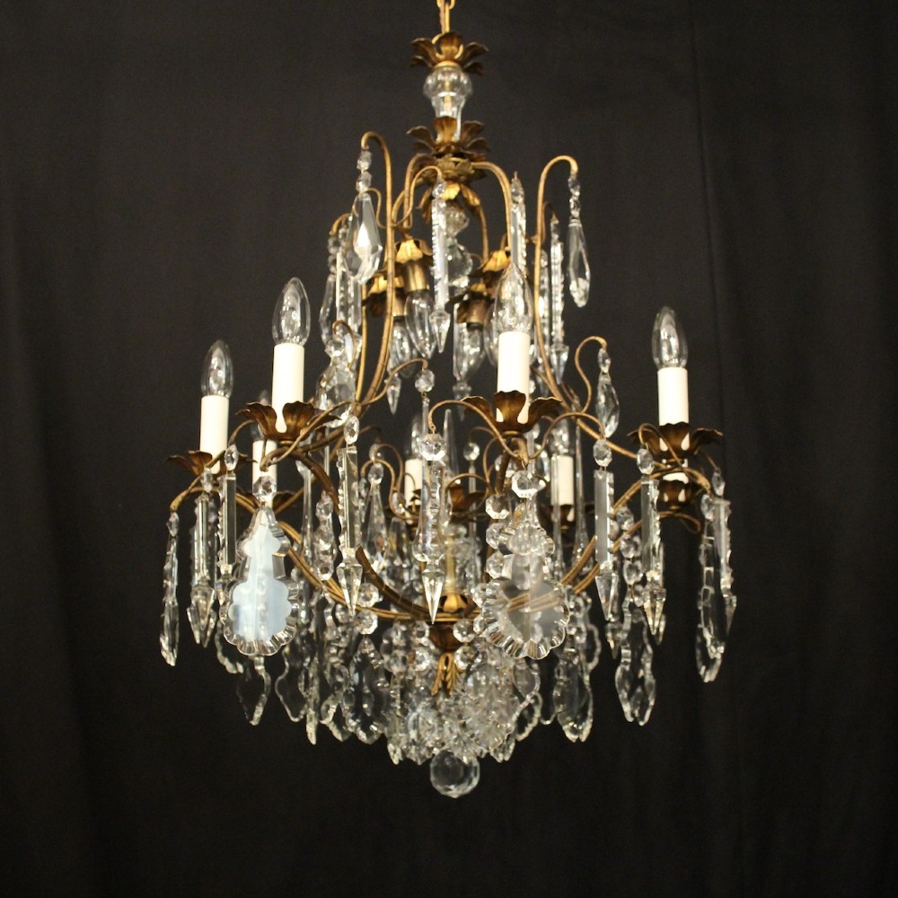 A multi-tiered French gilded brass chandelier adorned with cut crystal prisms and twelve faux candle light fittings. View II