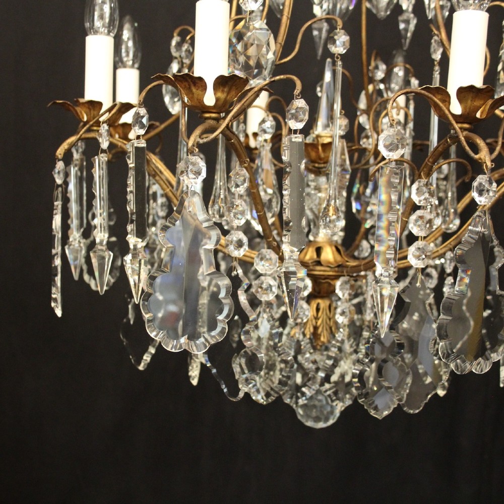 A multi-tiered French gilded brass chandelier adorned with cut crystal prisms and twelve faux candle light fittings. View V