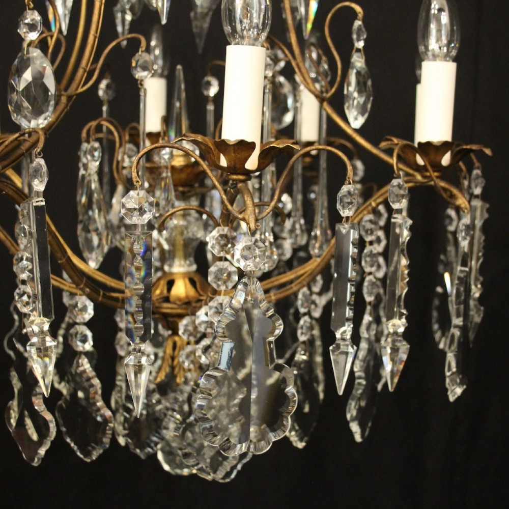 A multi-tiered French gilded brass chandelier adorned with cut crystal prisms and twelve faux candle light fittings. View VI