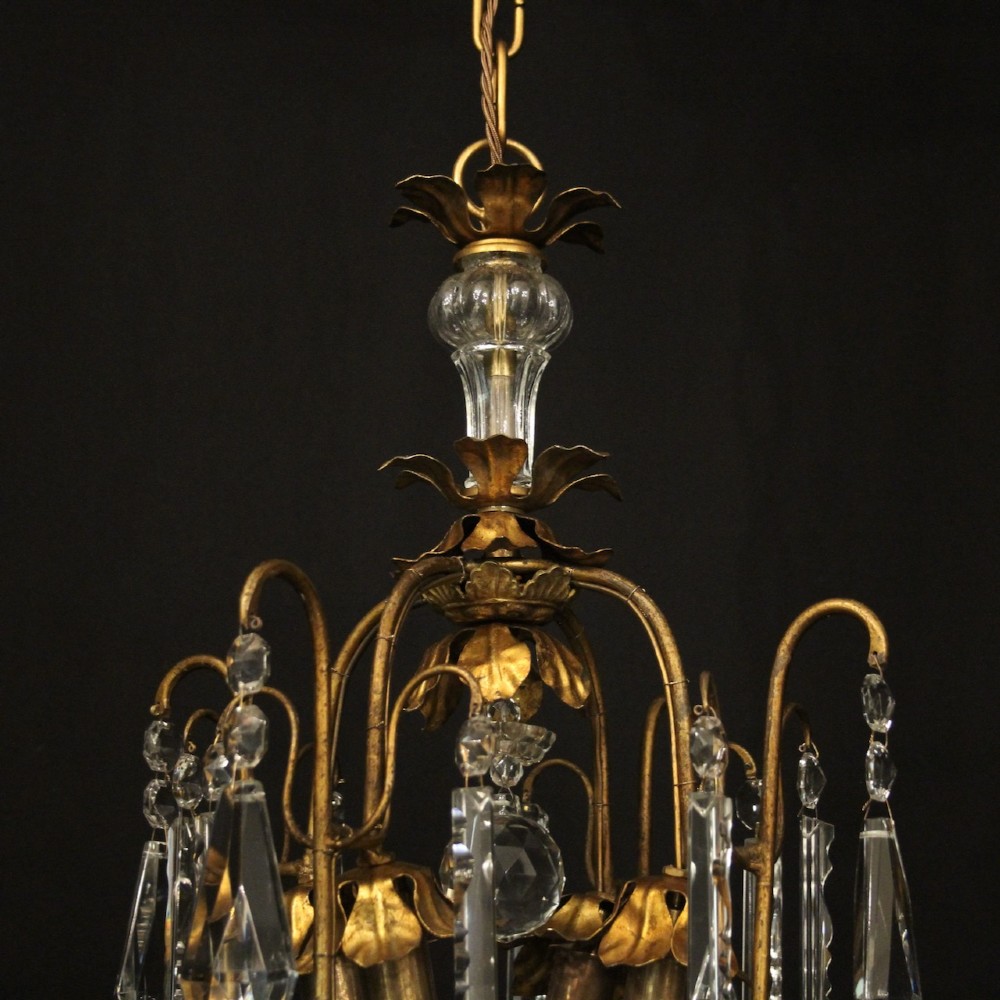 A multi-tiered French gilded brass chandelier adorned with cut crystal prisms and twelve faux candle light fittings. View VIII
