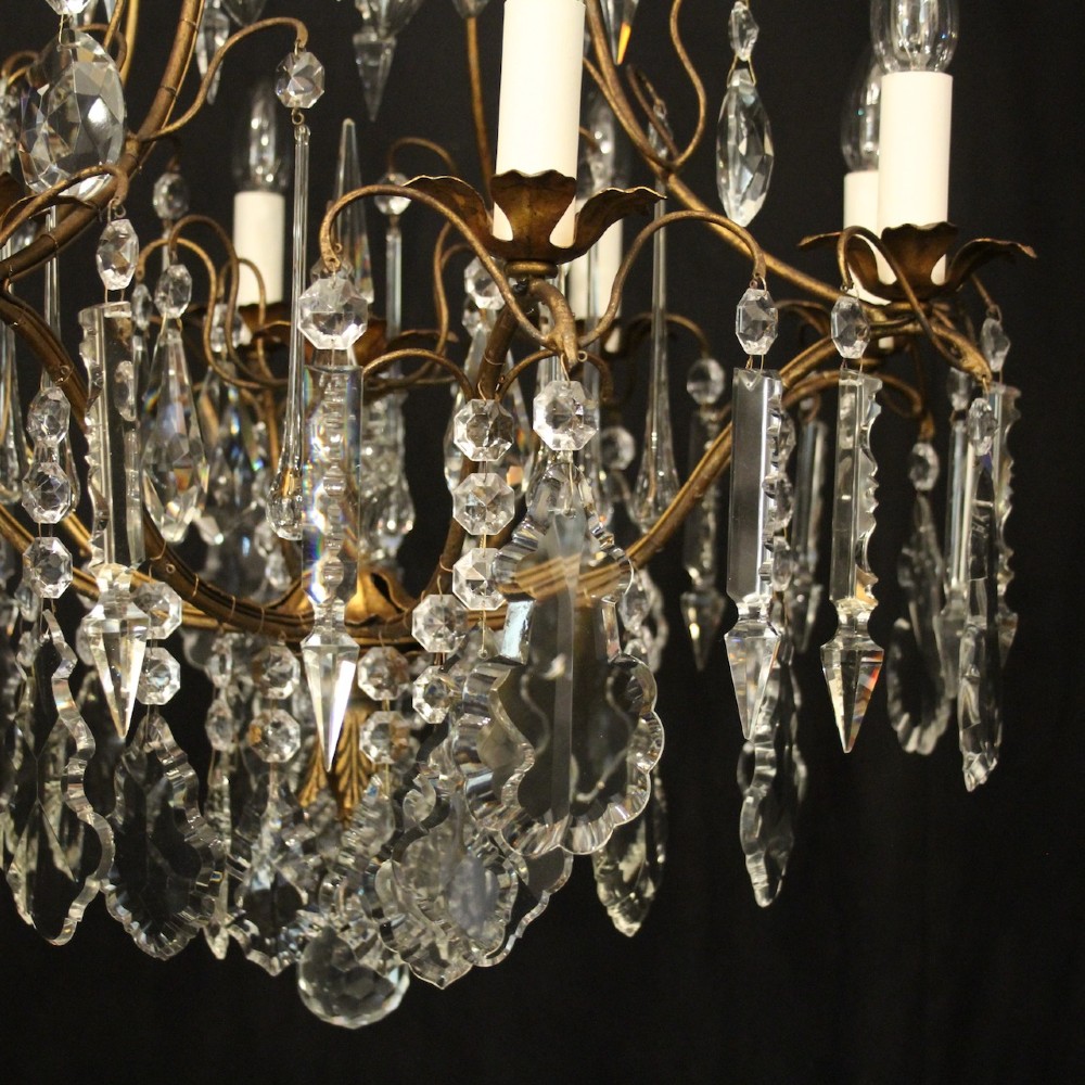 A multi-tiered French gilded brass chandelier adorned with cut crystal prisms and twelve faux candle light fittings. View IX