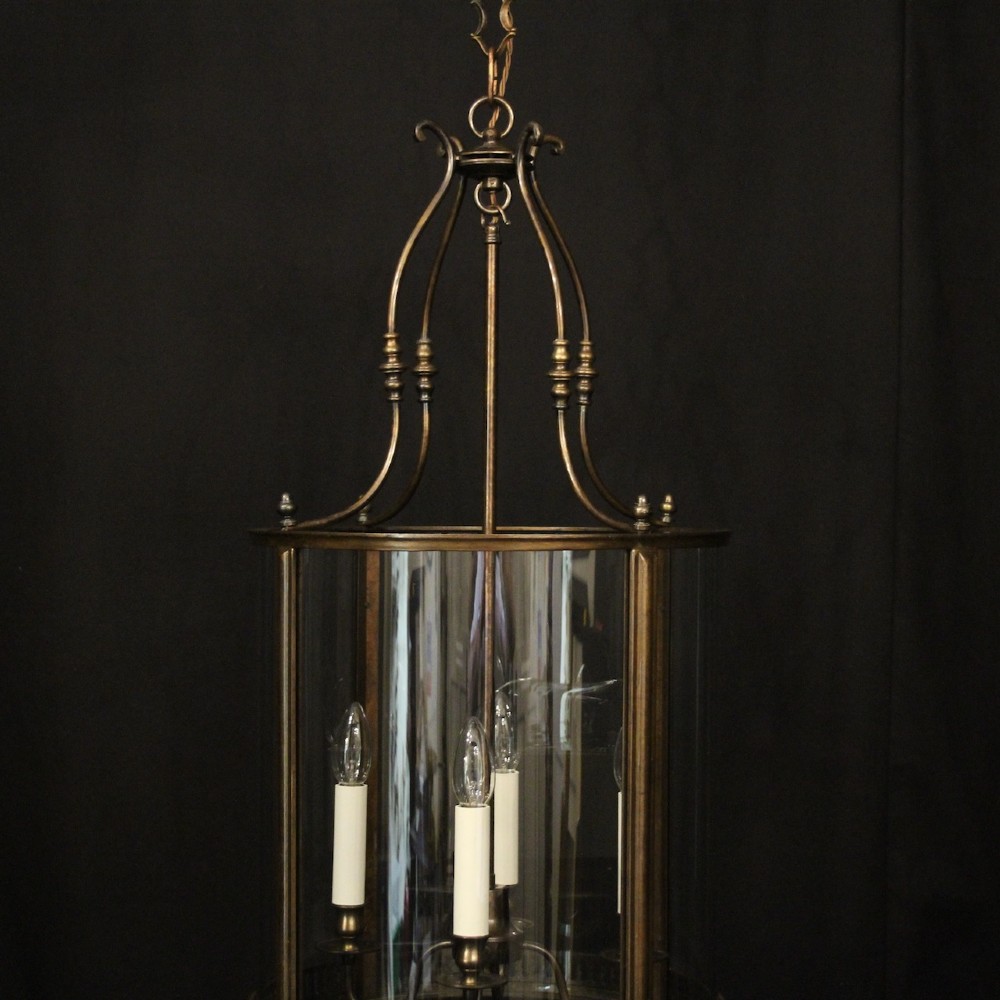 An English brass hall lantern featuring curved convex glass panels and four candle-style light sockets suspended from a central stem. View II