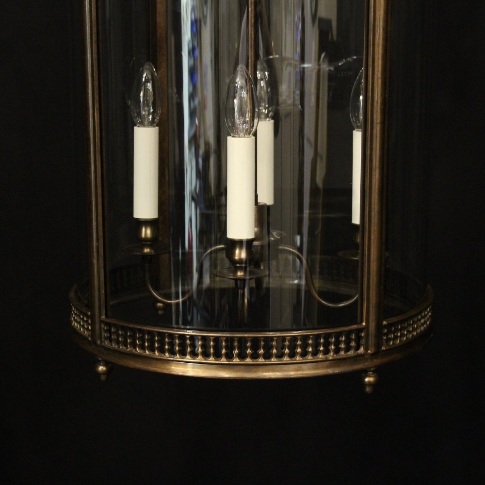 An English brass hall lantern featuring curved convex glass panels and four candle-style light sockets suspended from a central stem. View V