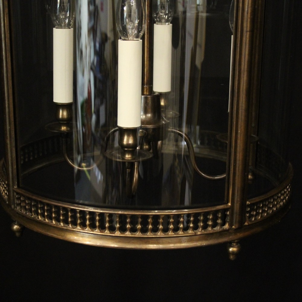 An English brass hall lantern featuring curved convex glass panels and four candle-style light sockets suspended from a central stem. View VI