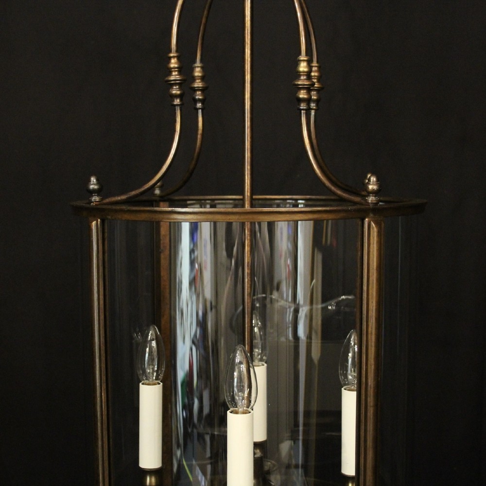 An English brass hall lantern featuring curved convex glass panels and four candle-style light sockets suspended from a central stem. View VII