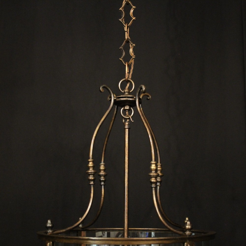 An English brass hall lantern featuring curved convex glass panels and four candle-style light sockets suspended from a central stem. View VIII