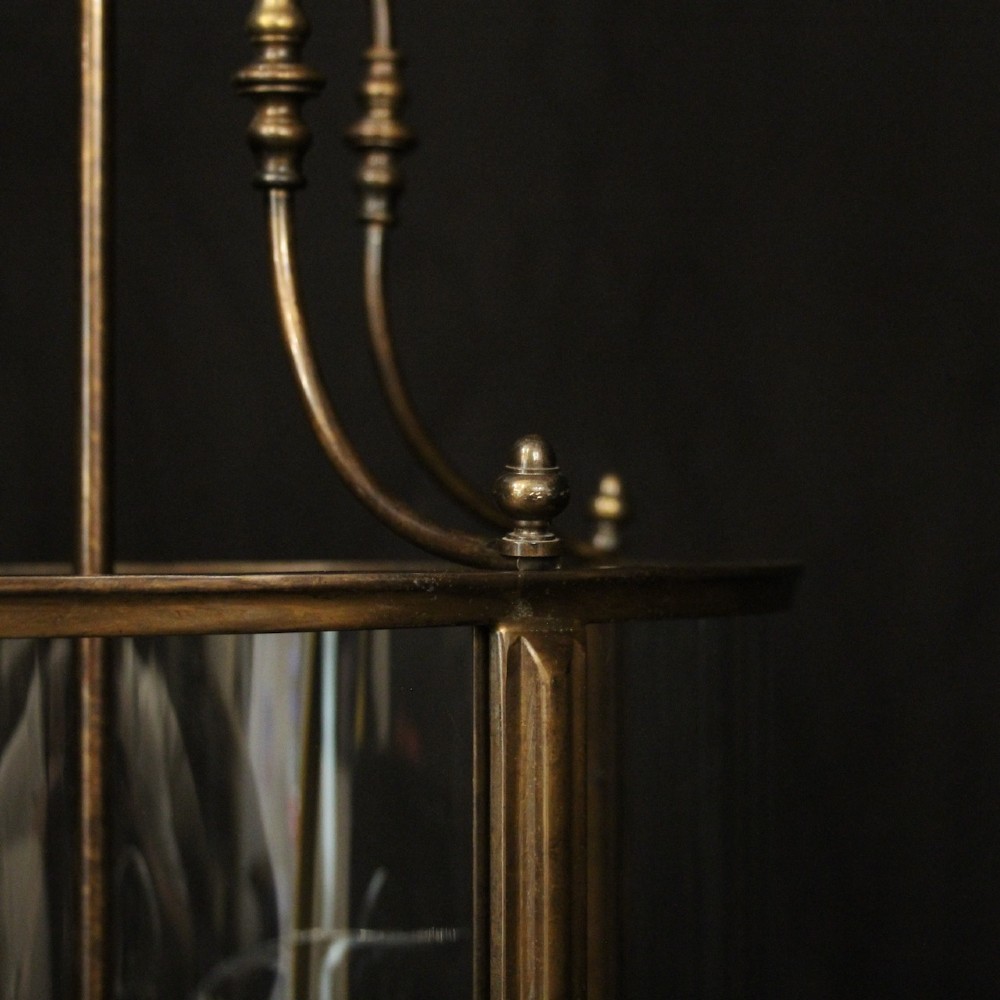 An English brass hall lantern featuring curved convex glass panels and four candle-style light sockets suspended from a central stem. View IX