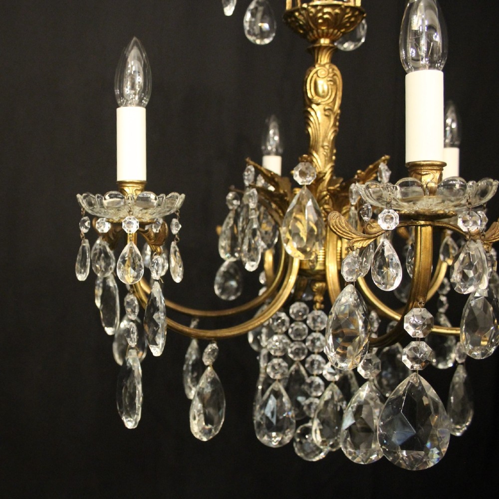 A six-arm French gilded brass chandelier decorated with faceted crystal drops and white candle-effect light sleeves. View II