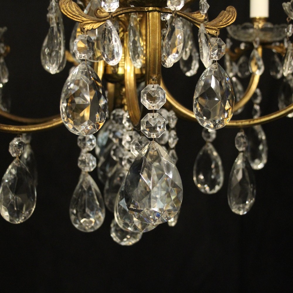 A six-arm French gilded brass chandelier decorated with faceted crystal drops and white candle-effect light sleeves. View V