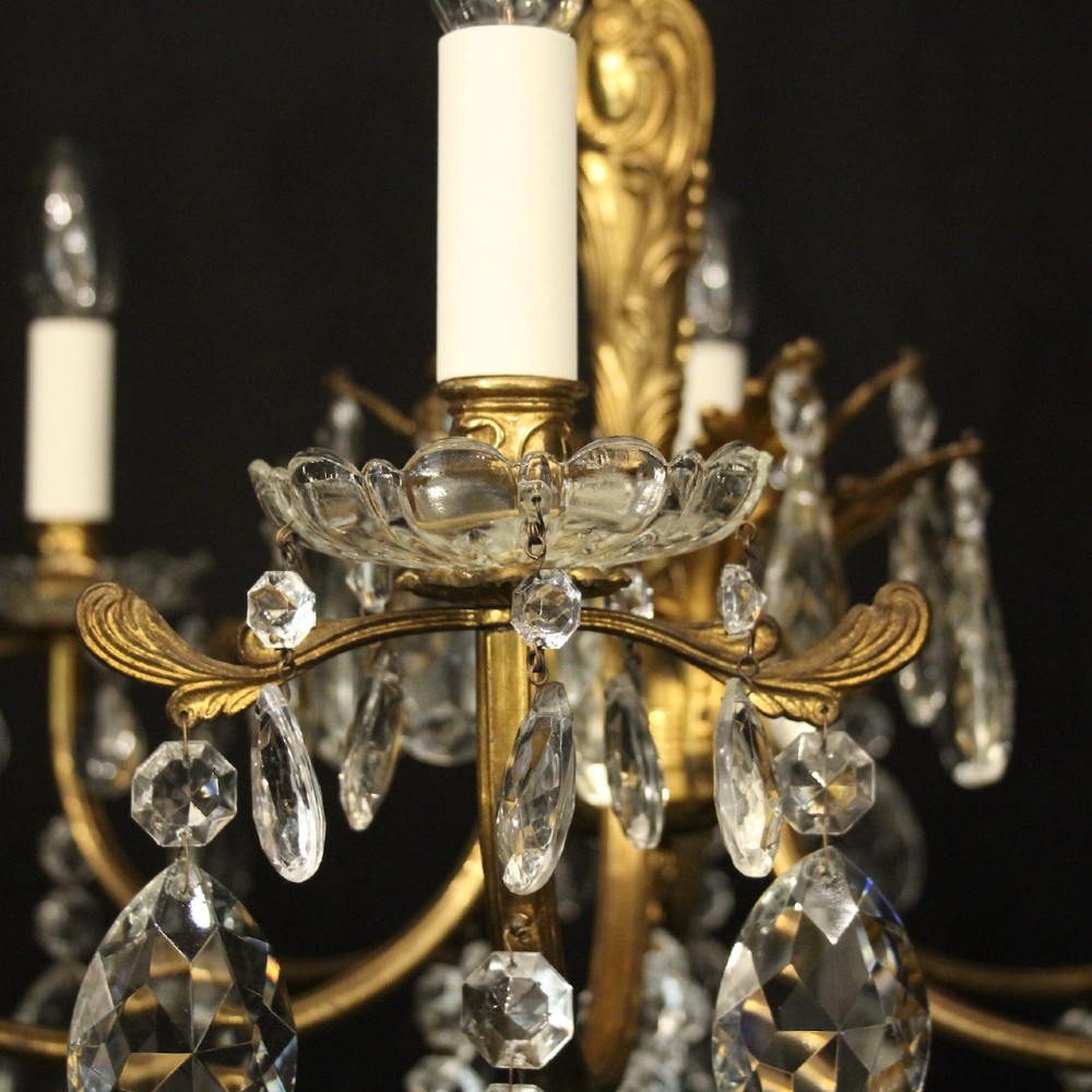 A six-arm French gilded brass chandelier decorated with faceted crystal drops and white candle-effect light sleeves. View VI
