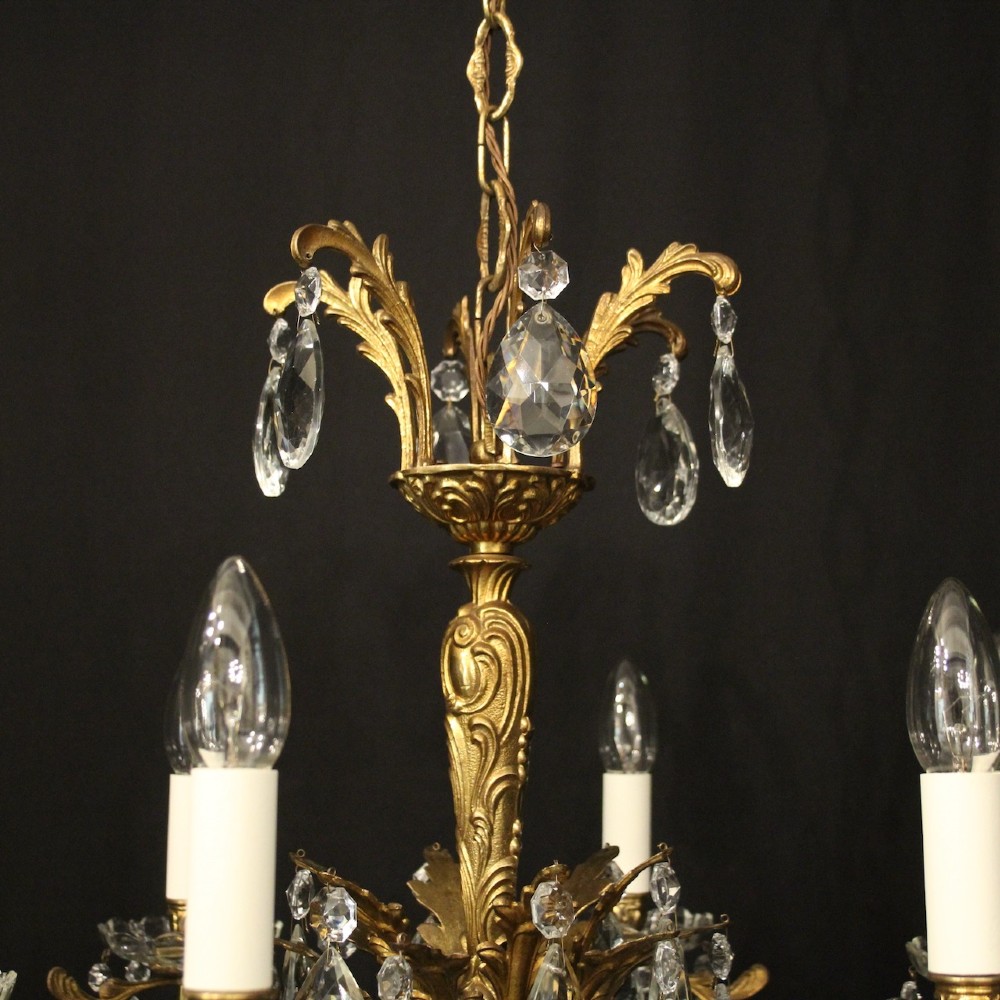 A six-arm French gilded brass chandelier decorated with faceted crystal drops and white candle-effect light sleeves. View IX