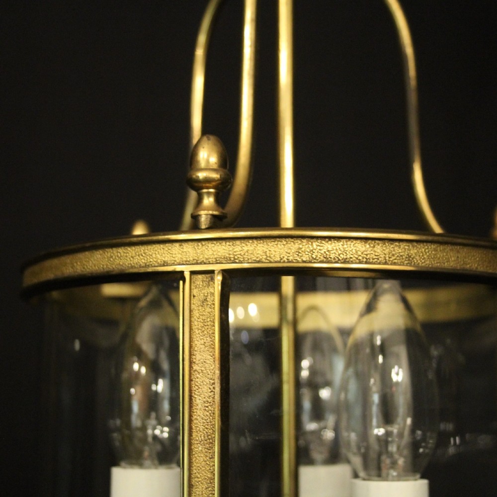 A French gilded brass hall lantern featuring a cylindrical glass shade enclosing three candle-style bulb holders suspended by an arched frame. View VIII
