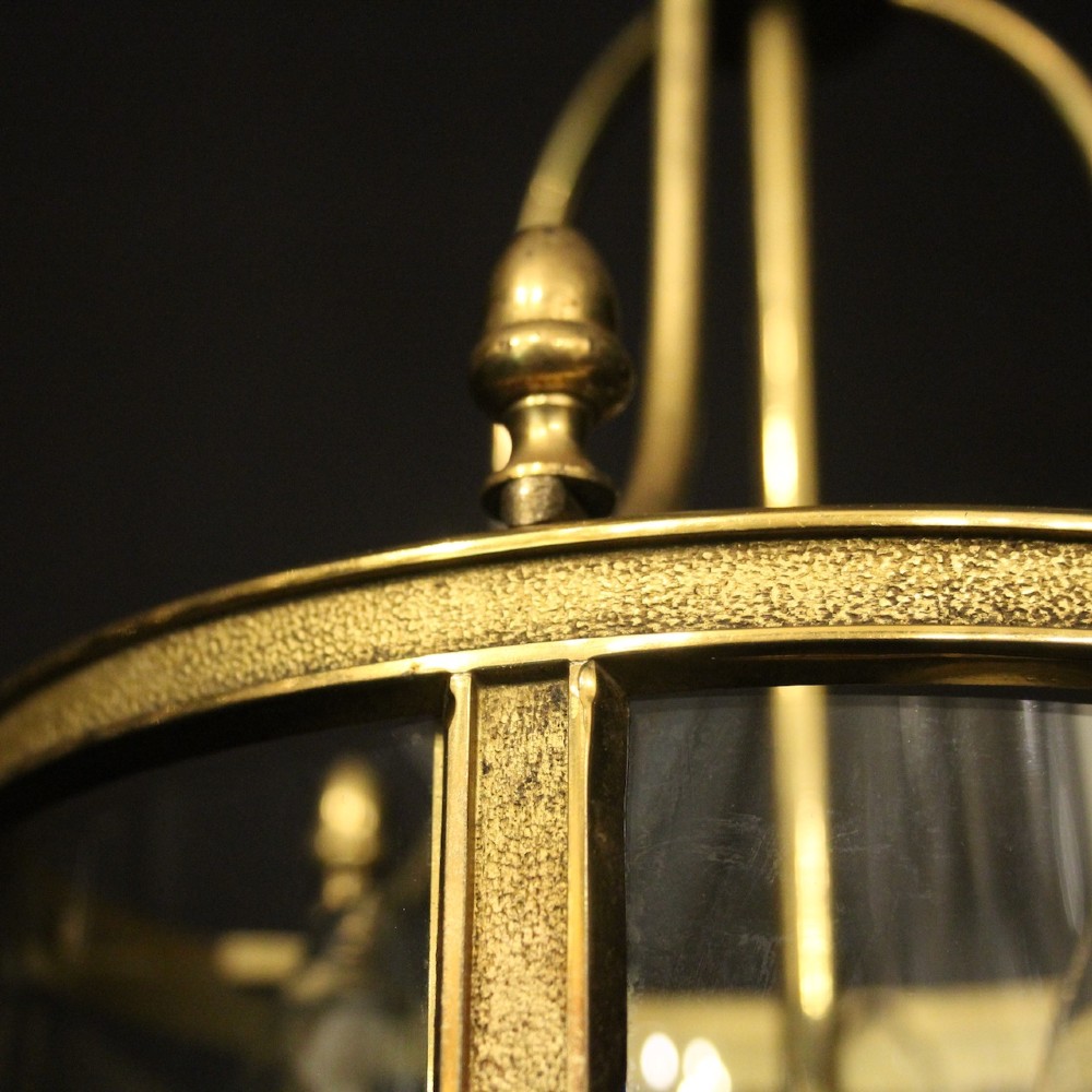 A French gilded brass hall lantern featuring a cylindrical glass shade enclosing three candle-style bulb holders suspended by an arched frame. View IX