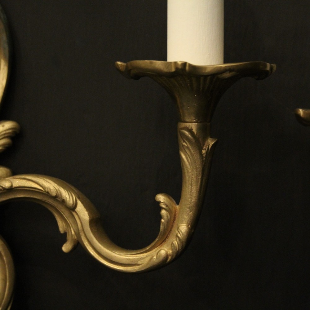 A pair of French gilt bronze twin-arm wall lights with scrolling acanthus leaf ornamentation and white candle sleeves. View VI