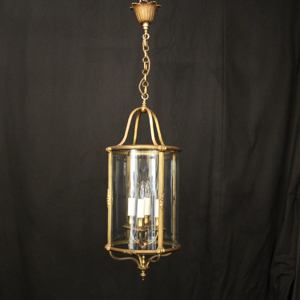 A cylindrical glass and gilt bronze hanging lantern featuring four internal candle sleeves, a looped upper crown, and a suspension chain. View II