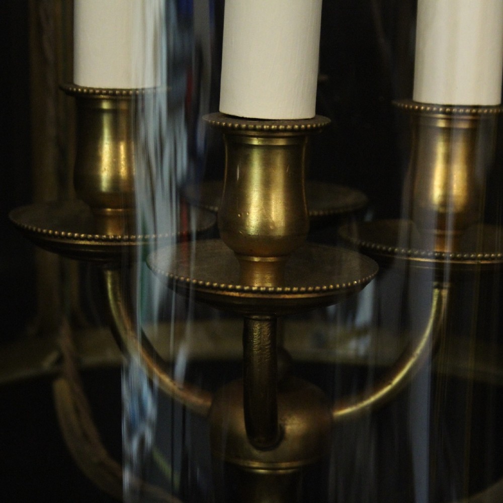 A cylindrical glass and gilt bronze hanging lantern featuring four internal candle sleeves, a looped upper crown, and a suspension chain. View V