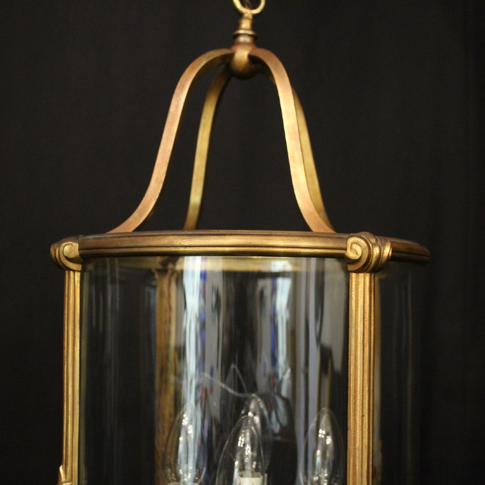 A cylindrical glass and gilt bronze hanging lantern featuring four internal candle sleeves, a looped upper crown, and a suspension chain. View VII