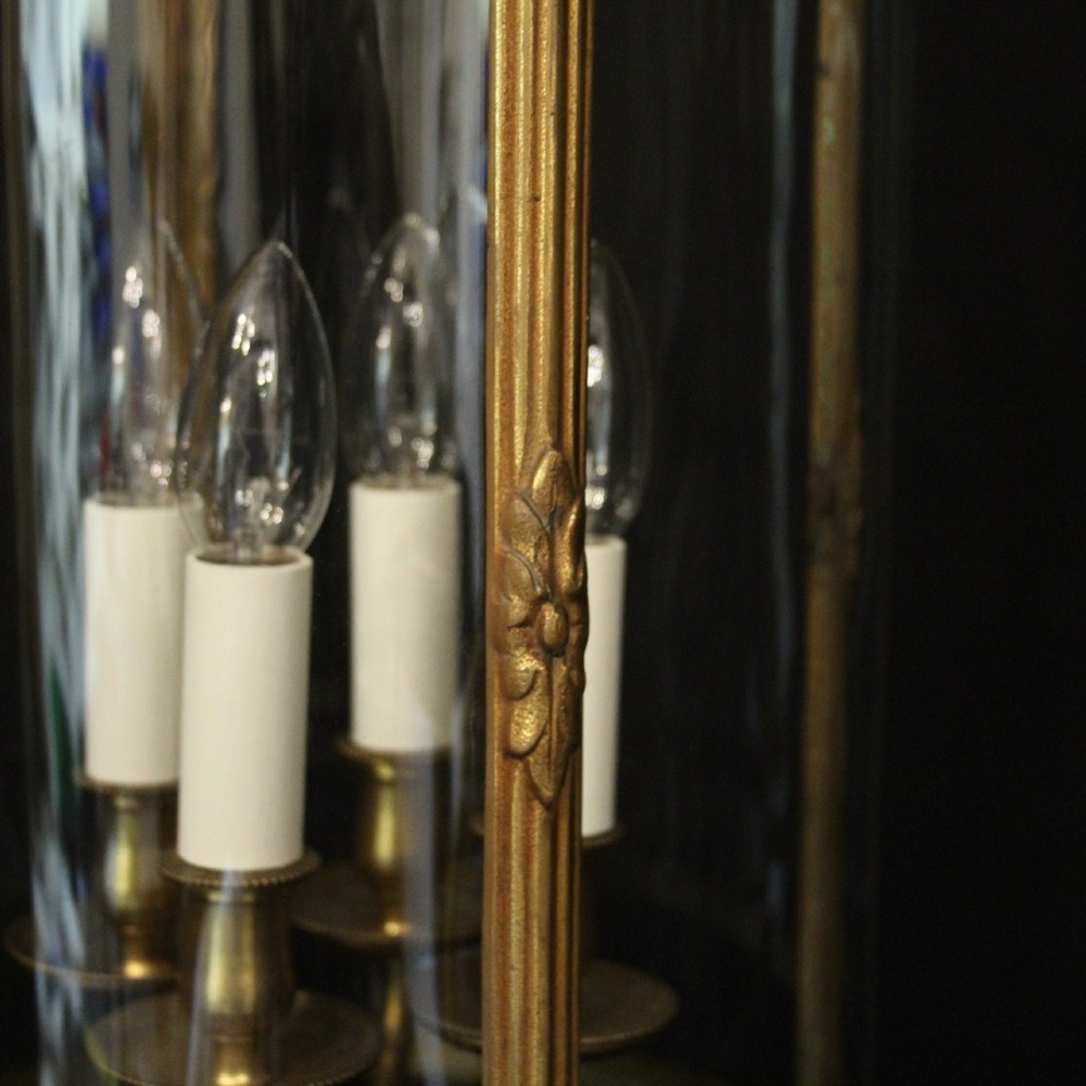 A cylindrical glass and gilt bronze hanging lantern featuring four internal candle sleeves, a looped upper crown, and a suspension chain. View IX