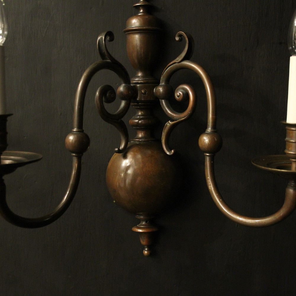 A pair of dark bronze twin-arm wall sconces featuring turned central shafts, scrollwork accents, and candle-style fittings. View III