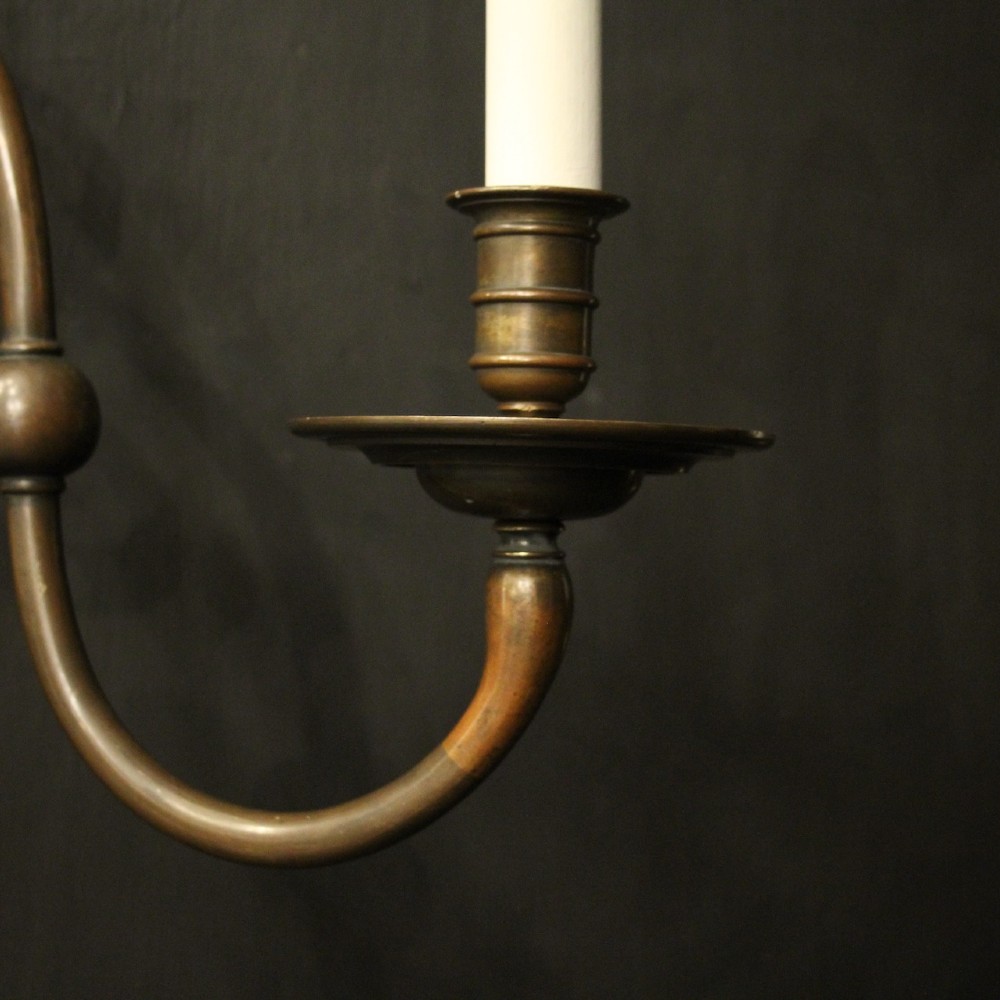 A pair of dark bronze twin-arm wall sconces featuring turned central shafts, scrollwork accents, and candle-style fittings. View VII