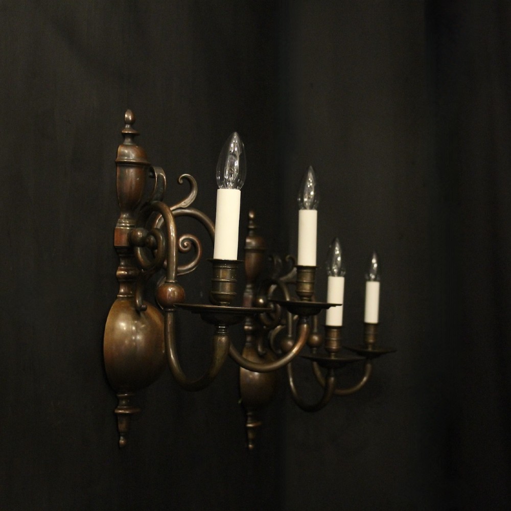A pair of dark bronze twin-arm wall sconces featuring turned central shafts, scrollwork accents, and candle-style fittings. View X