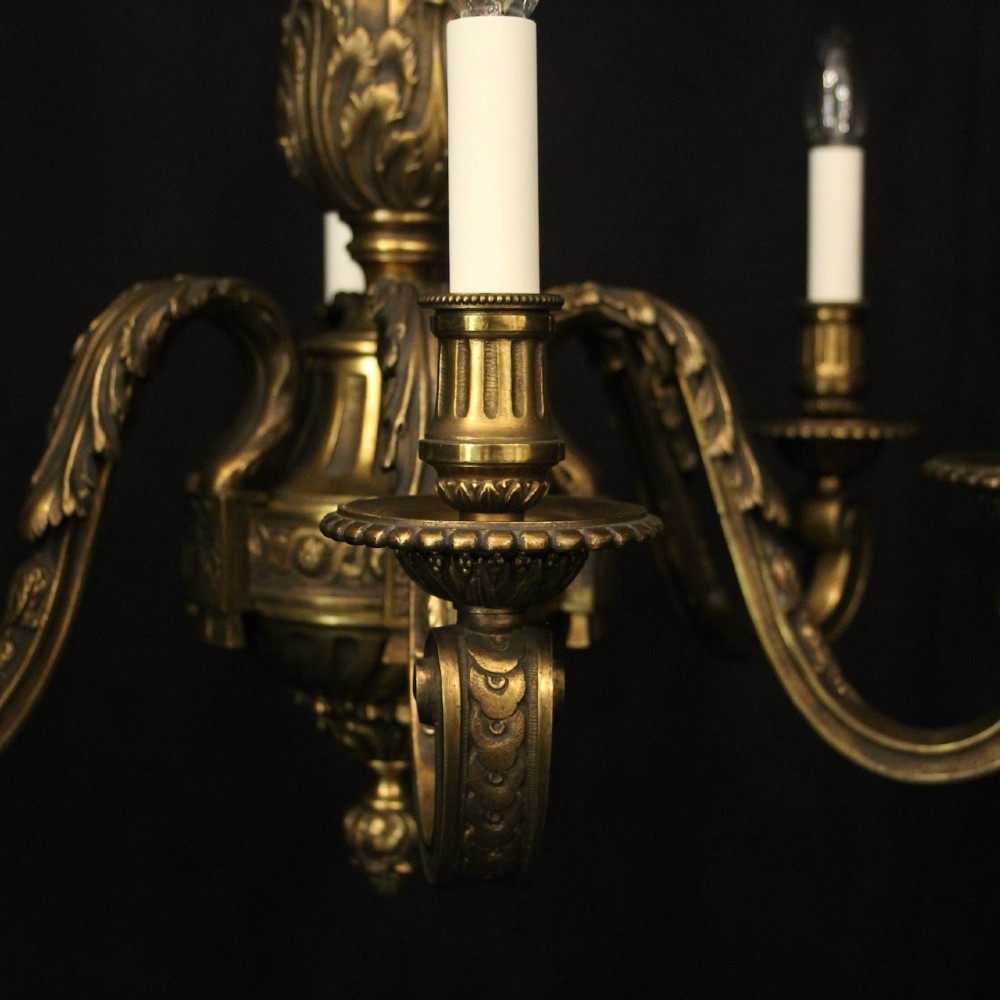 A nineteenth-century French gilded bronze chandelier with six curved arms featuring acanthus leaf motifs and white candle sleeves against a dark background. View VII
