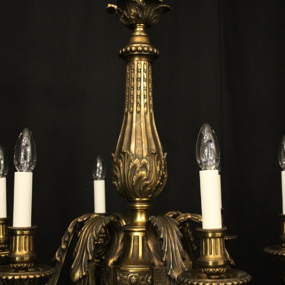 A nineteenth-century French gilded bronze chandelier with six curved arms featuring acanthus leaf motifs and white candle sleeves against a dark background. View IX