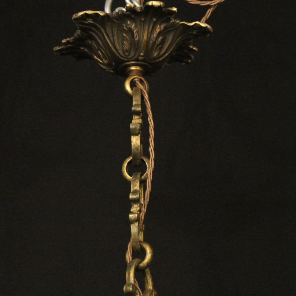 A nineteenth-century French gilded bronze chandelier with six curved arms featuring acanthus leaf motifs and white candle sleeves against a dark background. View X