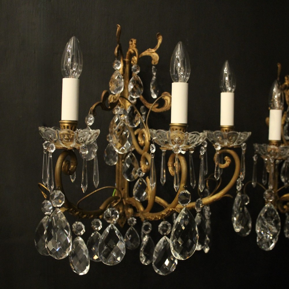A pair of French gilded metal triple-arm wall sconces adorned with faceted crystal teardrop pendeloques and candle-style sockets. View III