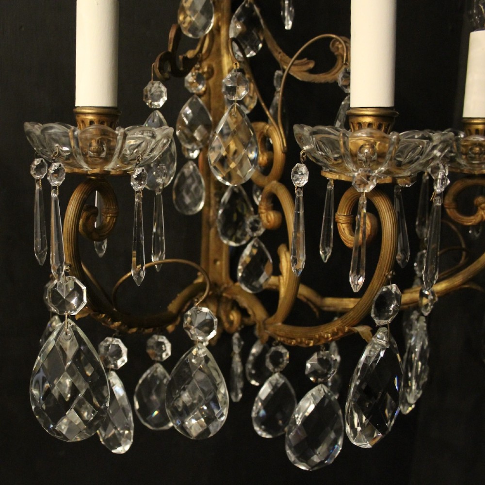 A pair of French gilded metal triple-arm wall sconces adorned with faceted crystal teardrop pendeloques and candle-style sockets. View IV
