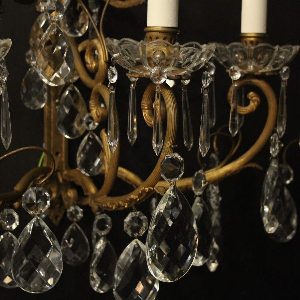 A pair of French gilded metal triple-arm wall sconces adorned with faceted crystal teardrop pendeloques and candle-style sockets. View VI