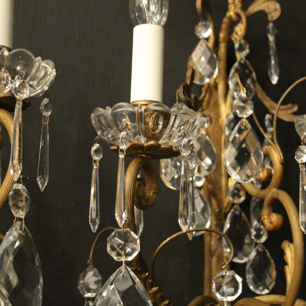 A pair of French gilded metal triple-arm wall sconces adorned with faceted crystal teardrop pendeloques and candle-style sockets. View VIII
