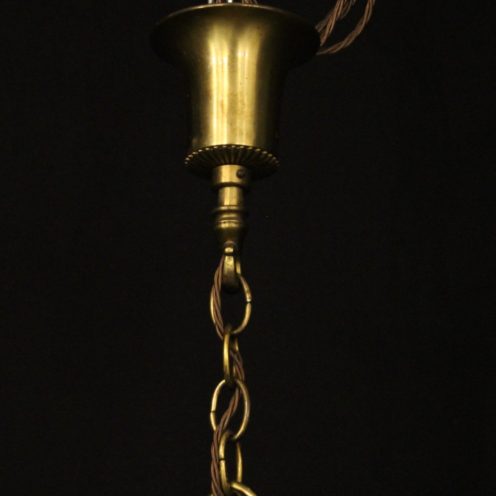 An eight-light antique gilded brass chandelier featuring ornate scrolled arms, candle-style sleeves, and a central turned baluster column. View X