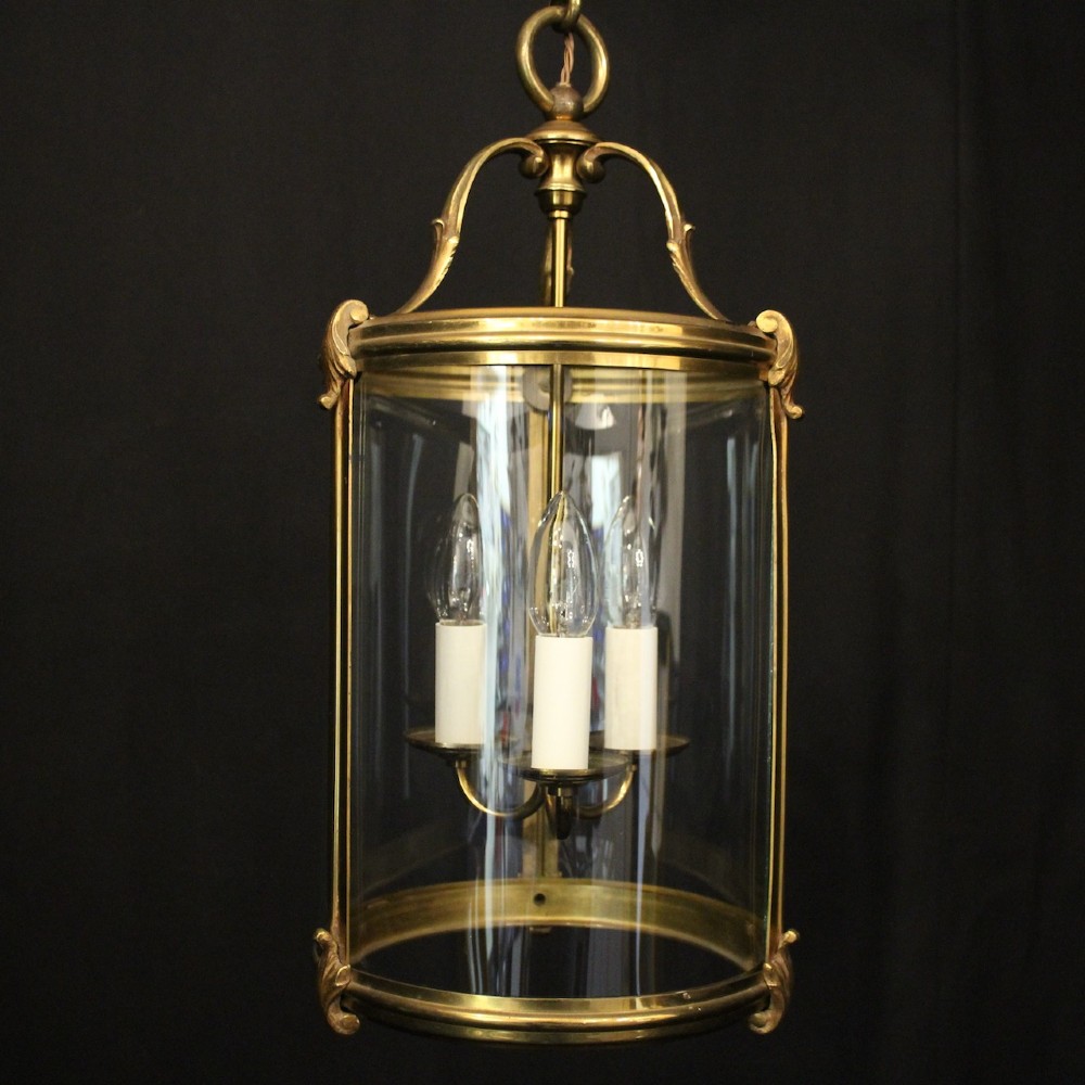 A cylindrical French hall lantern with a gilt brass frame, convex glass panels, and an internal three-light candelabra fitting suspended by a ring. View II