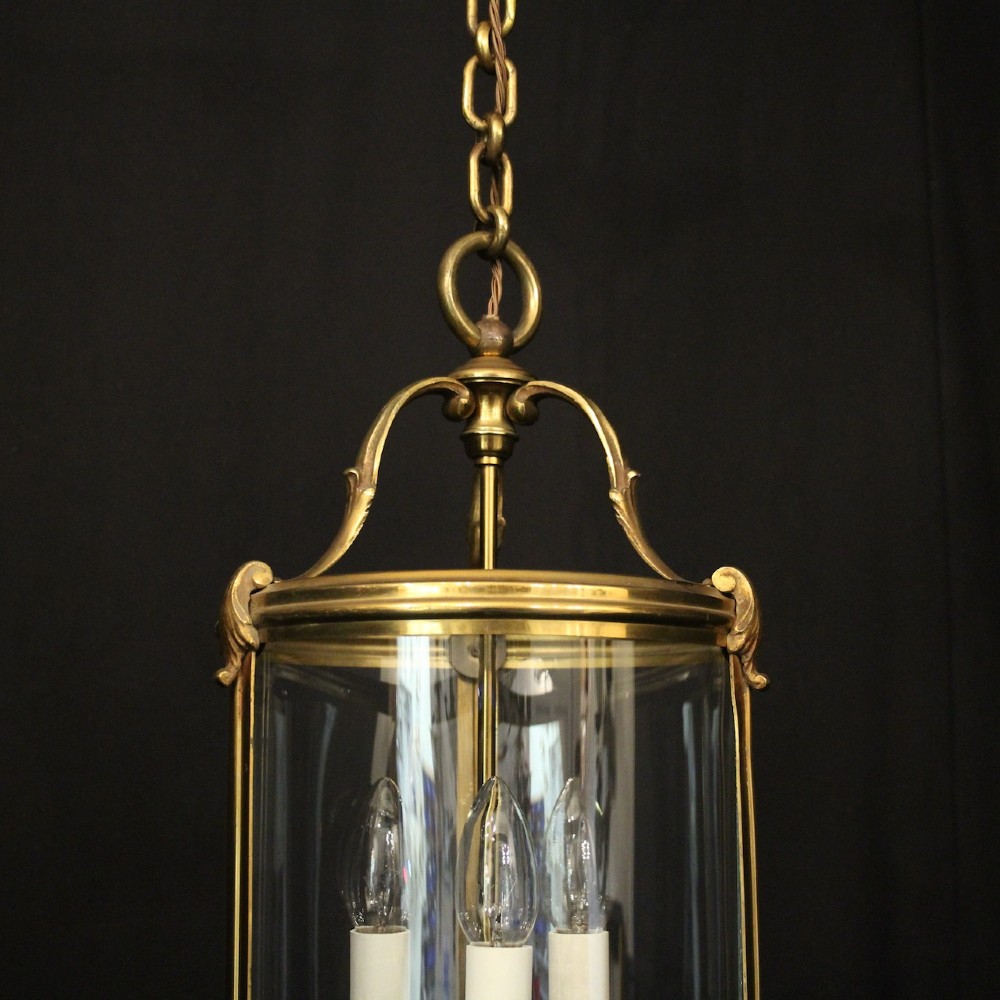 A cylindrical French hall lantern with a gilt brass frame, convex glass panels, and an internal three-light candelabra fitting suspended by a ring. View IV