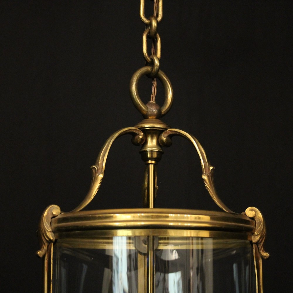 A cylindrical French hall lantern with a gilt brass frame, convex glass panels, and an internal three-light candelabra fitting suspended by a ring. View V
