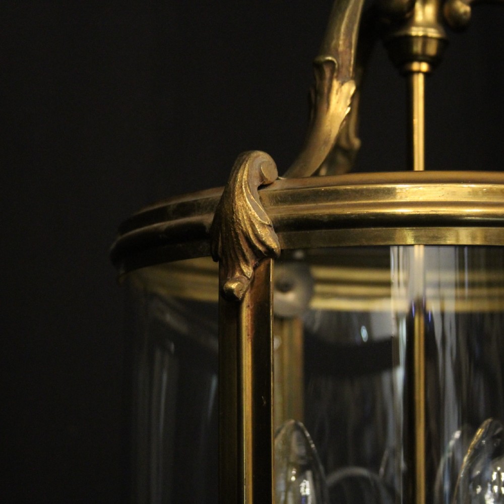 A cylindrical French hall lantern with a gilt brass frame, convex glass panels, and an internal three-light candelabra fitting suspended by a ring. View VII
