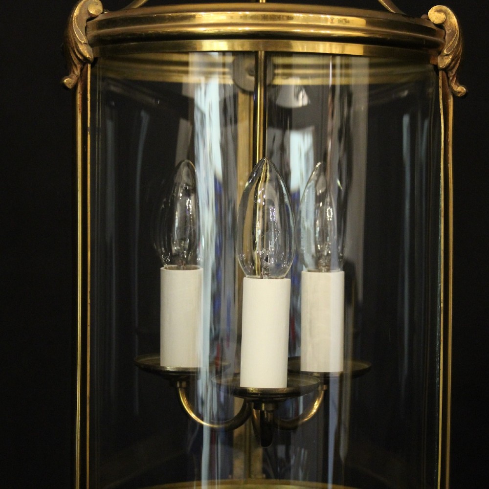 A cylindrical French hall lantern with a gilt brass frame, convex glass panels, and an internal three-light candelabra fitting suspended by a ring. View IX