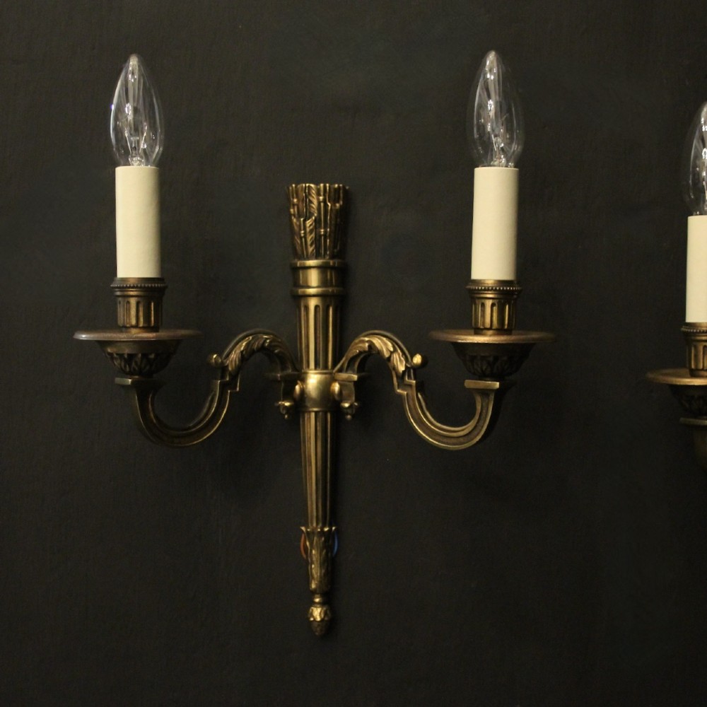 A set of four French Empire style gilded metal wall sconces, each featuring a central torch-shaped backplate and two curving candle arms. View II