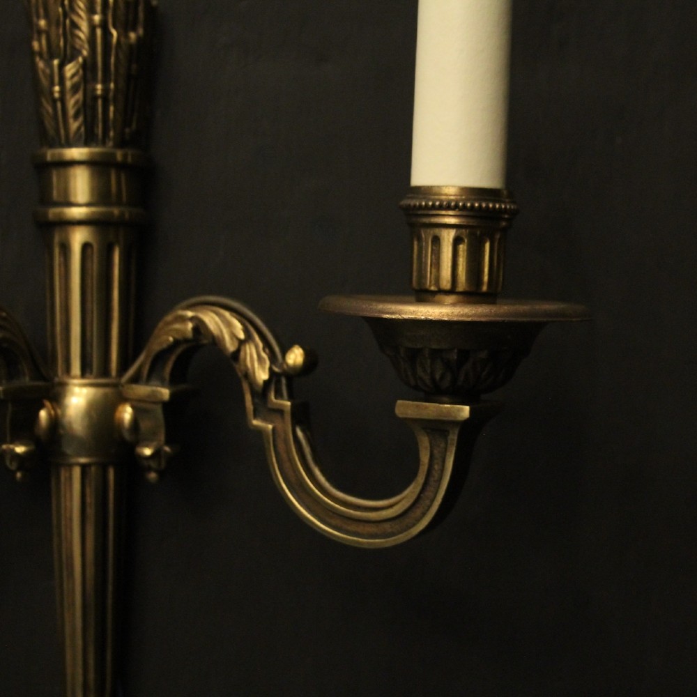A set of four French Empire style gilded metal wall sconces, each featuring a central torch-shaped backplate and two curving candle arms. View V