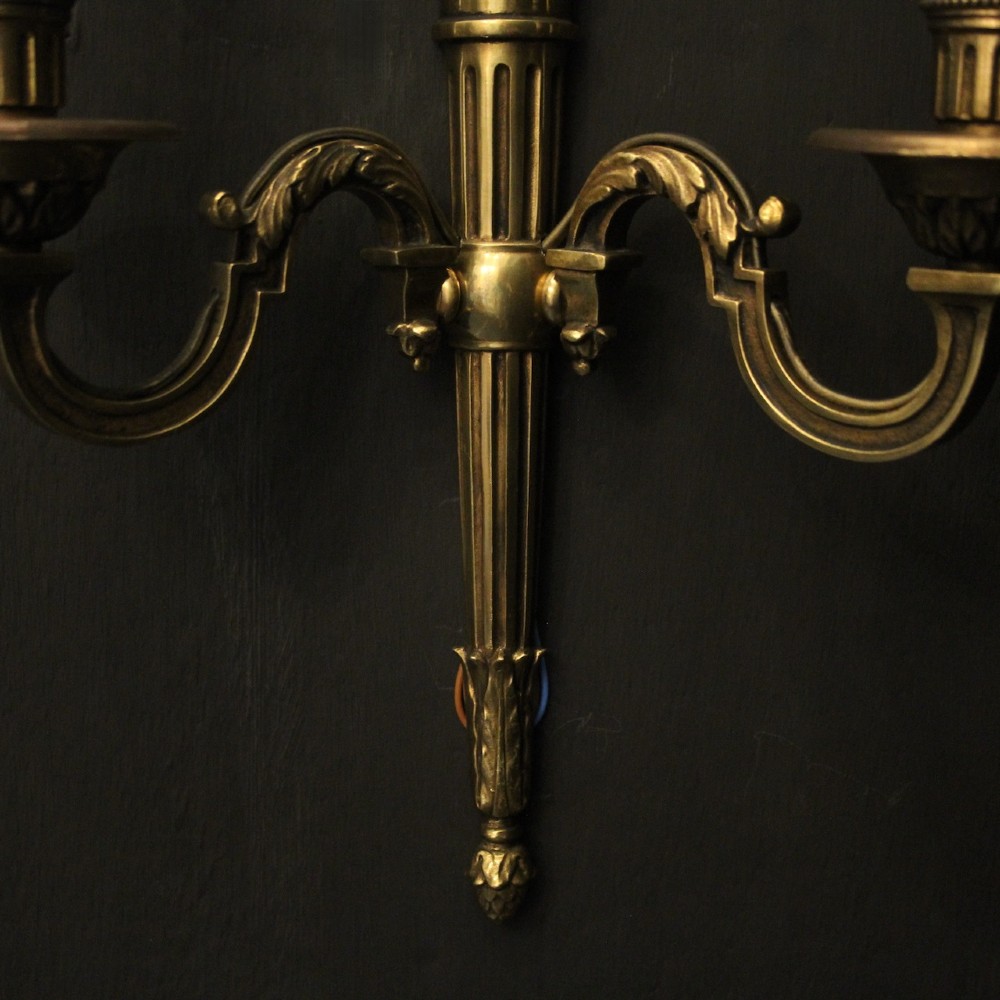 A set of four French Empire style gilded metal wall sconces, each featuring a central torch-shaped backplate and two curving candle arms. View VIII