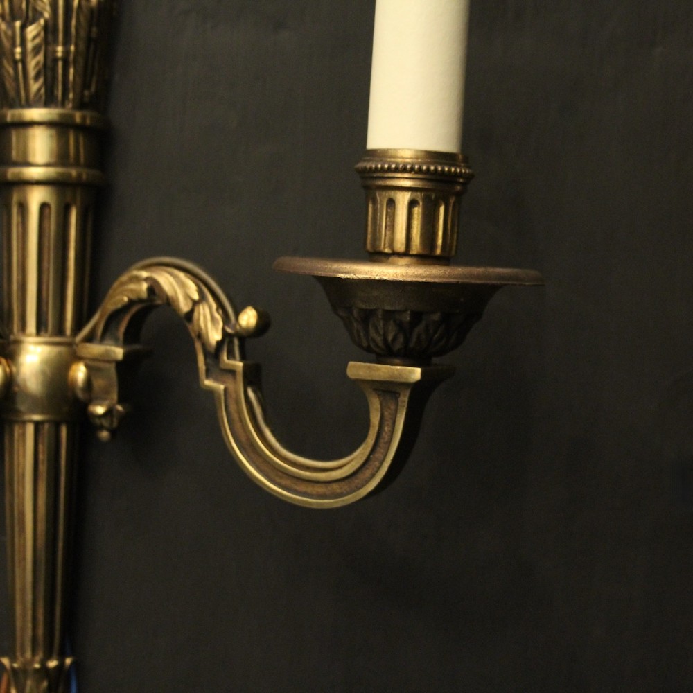 A set of four French Empire style gilded metal wall sconces, each featuring a central torch-shaped backplate and two curving candle arms. View IX