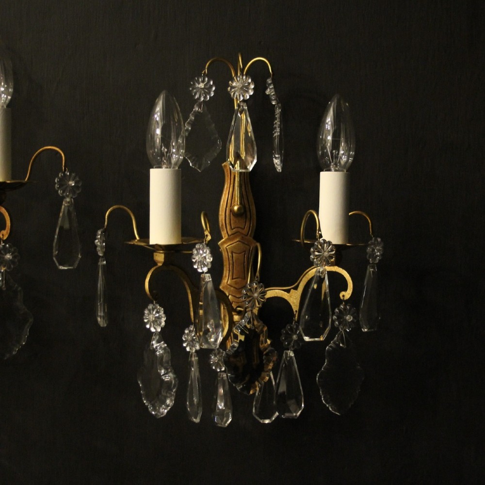 A pair of French gilded wall lights featuring twin candle-style bulb sockets, scrolling metal arms, and hanging faceted crystal droplets. View II