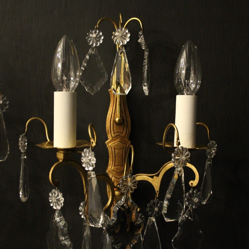 A pair of French gilded wall lights featuring twin candle-style bulb sockets, scrolling metal arms, and hanging faceted crystal droplets. View III