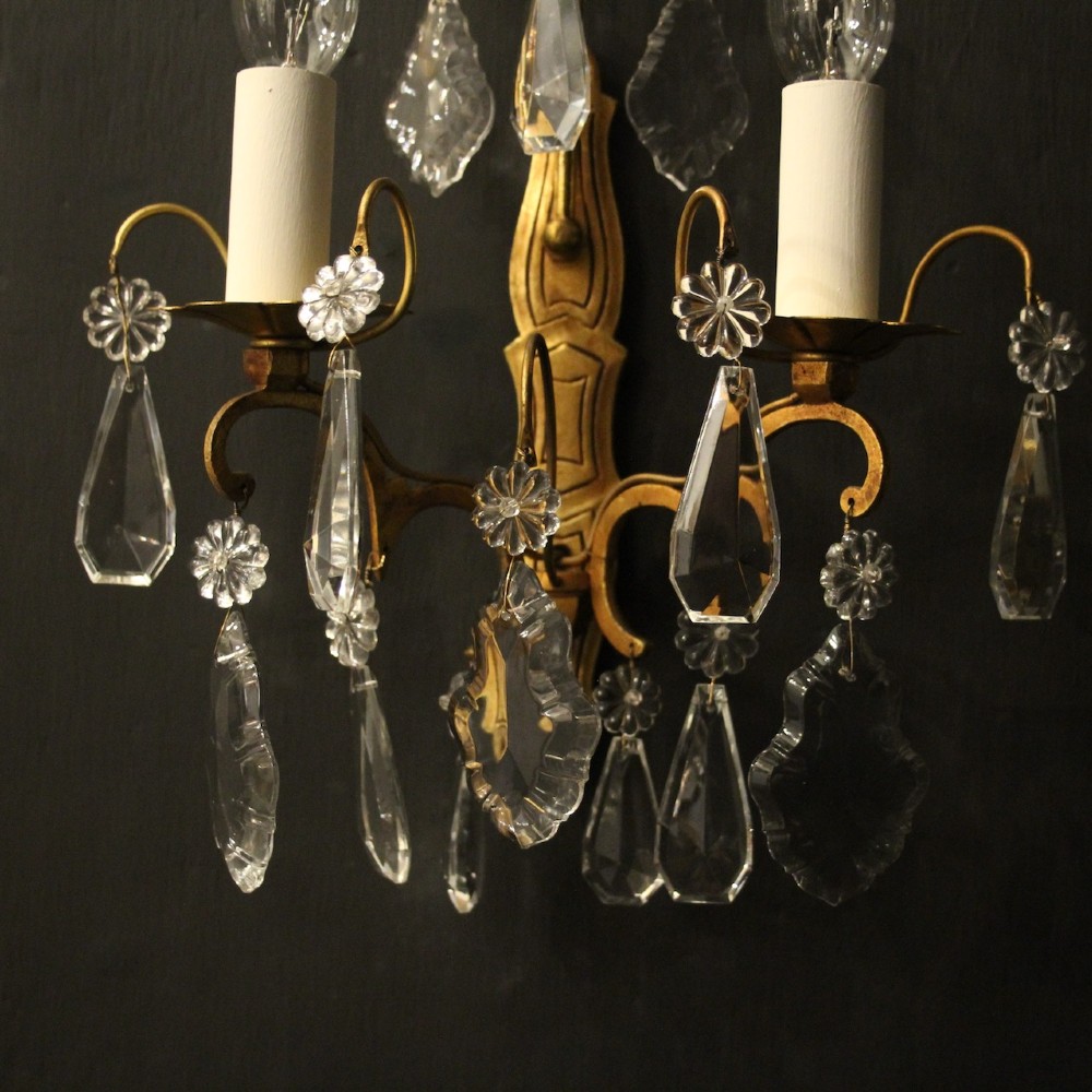 A pair of French gilded wall lights featuring twin candle-style bulb sockets, scrolling metal arms, and hanging faceted crystal droplets. View IV