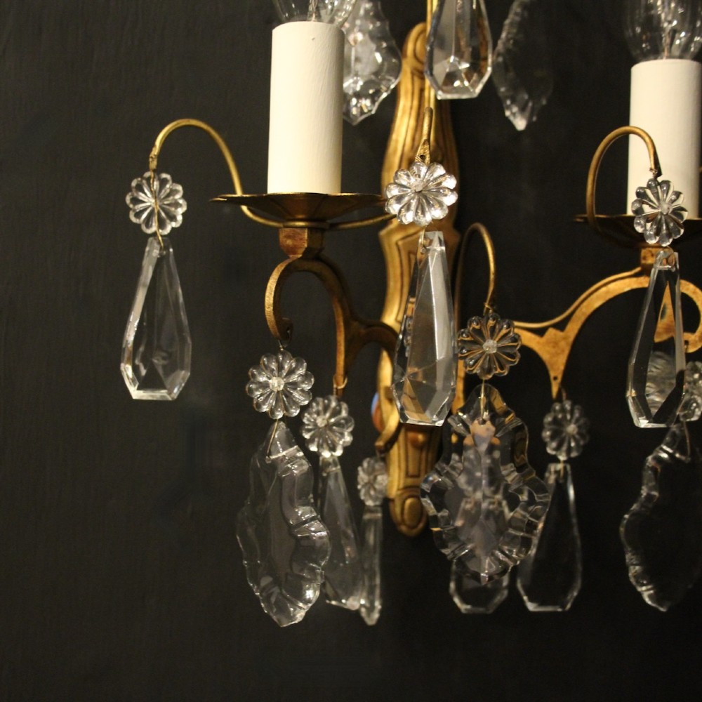 A pair of French gilded wall lights featuring twin candle-style bulb sockets, scrolling metal arms, and hanging faceted crystal droplets. View V